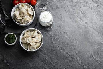 Tasty dumplings in bowls served on grey table, flat lay. Space for text