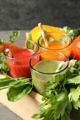 Delicious vegetable juices and fresh ingredients on grey table