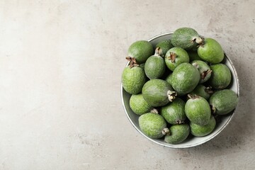 Fresh green feijoa fruits in bowl on light grey table, top view. Space for text