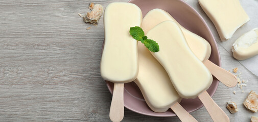 Delicious glazed ice cream bars, chocolate and mint on white wooden table, flat lay with space for...