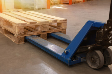 Modern manual forklift with wooden pallets in warehouse, closeup