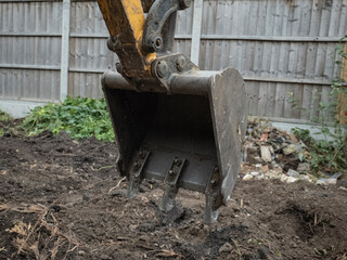 Fototapeta na wymiar close up of mini digger bucket excavating the ground in a garden work site