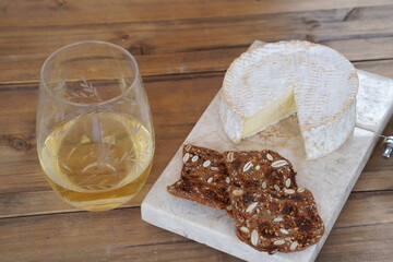 Camembert Cheese on White Marble, Whiet Reisling Wine and Brown Seeded Crackers on Dark Panelling