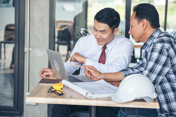 Contractor construction engineer meeting talking together on architect table at construction office site. Businessman engineer manager discuss with foreman team builder look at plan blueprint laptop