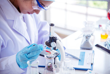 Woman scientist hand write note information in medical lab look at science microscope medical test,...
