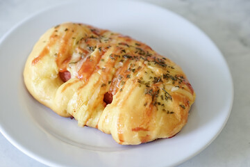 Sausage buns bread. Soft baked bun (dough) stuffed with sausage for fast food breakfast or coffee break. Sausage roll, (hot dog). With mayo, tomato sauce, mozarella cheese and parsley topping
