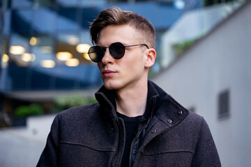 Closeup fashion shot, young man in coat and sunglasses fall fashoin 
