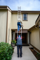 Fall maintenance, senior man climbing a ladder with a leaf blower, senior woman holding the ladder steady  © knelson20