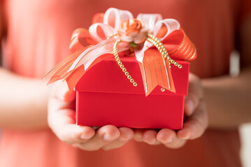 Red gift box with ribbon in hand, Present for giving in special day and holiday