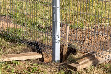 Installation of a metal fence. The process of installing support poles. Pit in the ground