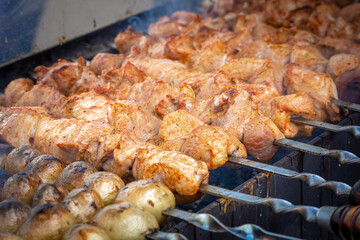 Outdoor street food. Marinated pork shashlik and potatoes roasted on a charcoal grill. A traditional Caucasian dish
