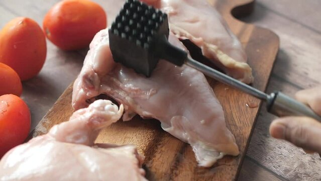 precessing raw chicken breast on a chopping board 