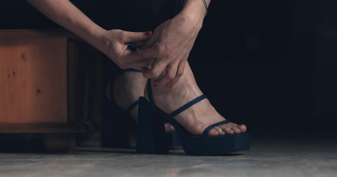 Close up of young woman tying her high heels and walking away.