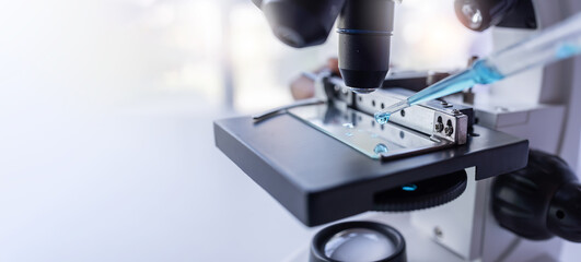 Researchers working in the clinical laboratory, shot of microscope with metal lens.