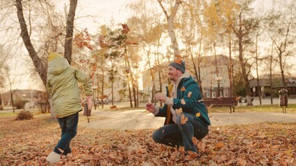 father and little child in an autumn park throw dry leaves up, happy family, live fun with dad,...