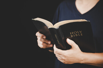Young woman person hand holding holy bible with study at home. Adult female christian reading book...