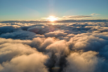 Aerial view from airplane window at high altitude of dense puffy cumulus clouds flying in evening
