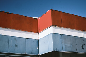 corner detail of weathered vintage red, white and blue trim of a building against the blue sky