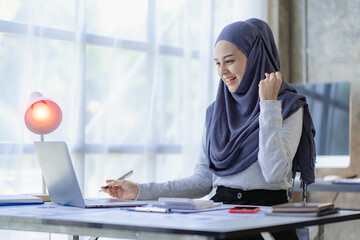 A Muslim business woman is very excited to close the sale. Arab woman smiling and working on laptop with financial chart