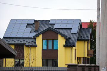 Residential house with rooftop covered with solar photovoltaic panels for producing of clean ecological electrical energy in suburban rural area. Concept of autonomous home