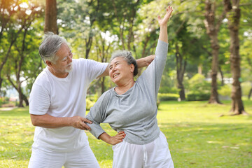 Asian senior couple practice yoga excercise, tai chi tranining, stretching and meditation together with relaxation for healthy in park outdoor after retirement. Happy elderly outdoor lifestyle concept