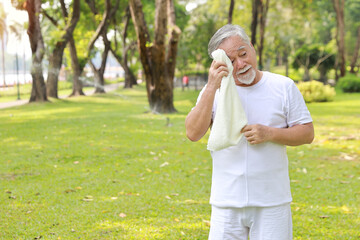 Obraz premium Tired heat and hot asian senior man practice yoga excercise, tai chi tranining and stretching while wipe the sweat away for healthy in park outdoor. Happy elderly outdoor lifestyle concept