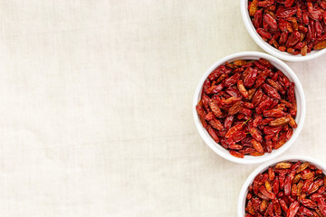 Dried Barberry berries in round ceramic white plates, top view on table. Ripe dry sour-tasting berries, healthy seasoning for food. Red Barberry natural food. Healthy and tasty spice