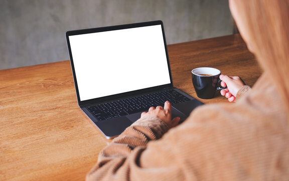 Mockup image of a woman using and typing on laptop computer with blank white desktop screen while drinking coffee