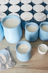 Jars of milk ready for ripening and turning into yogurt. The process of producing homemade yogurt. Vertical photo.