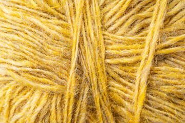 Fototapeta premium Macro texture of woolen yellow thread, close-up, copy space. Macro Photography of a coil with threads. Sewing background, screensaver. Abstraction, interweaving of natural threads