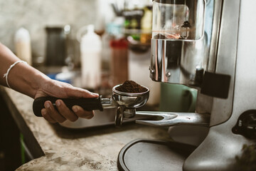 barista use bottomless filter with grinder machine at coffee shop. coffee maker concept.