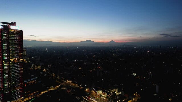 Aerial view rising over the illuminated Chapultepec Avenue, over the Roma Nte district, dusk in Mexico city