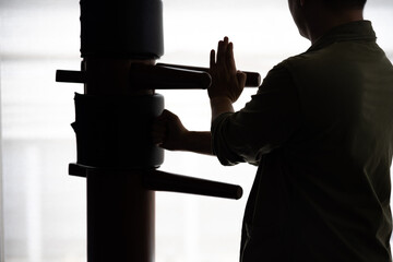 Silhouette of a fighter Wing Chun and wooden dummy on a background. Wing Chun Kung Fu Self defense - obrazy, fototapety, plakaty