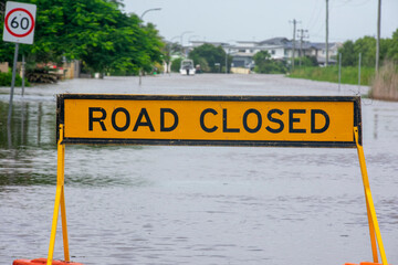 Road closed sign with flooded street beyond