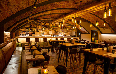 Interior of cozy modern restaurant with a bar counter and lamp lighting - obrazy, fototapety, plakaty