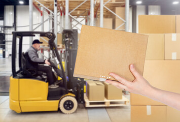 Box in hand of storekeeper. Warehouse processing of goods. Blurred forklift loading pallets....