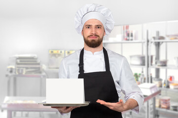 Chef is man. Chef with empty sign on tray. Guy cook in kitchen of restaurant. White sheet of paper in hands of chef. Restaurant worker recommends. Copy space. Young man cook. Selective focus.