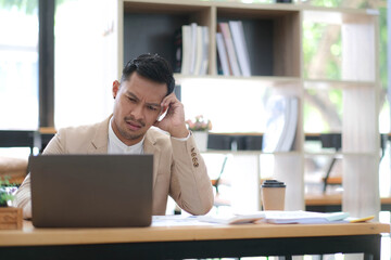 Obraz premium Tired frustrated young asian businessman feeling stressed holding head with hands, business problem failure concept