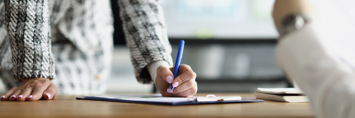 Woman in the office signs documents, close-up
