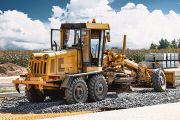 Road grader at the construction site. Powerful construction machine for ground leveling and excavation. Close-up. Professional construction equipment.