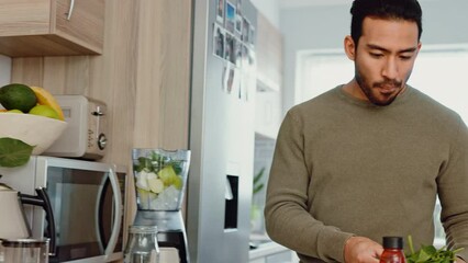 Man makes a healthy smoothie in kitchen with fruit and vegetables for a fresh snack. A positive lifestyle starts with good diet, cooking green food if hungry and home exercise for your body wellbeing