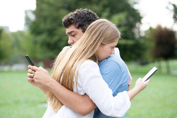 Teenager couple hugging and using phone at the same time. Social media and digital addiction concept