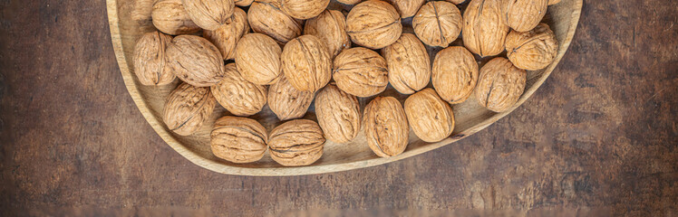 Walnuts on dark vintage table top view. Fresh Walnuts kernels in wooden plate. Copyspace