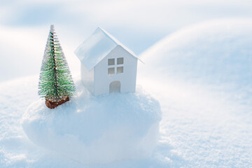 Decorative white house with a spruce tree in the snow in the sunlight outdoors, free space