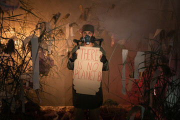 man in a gas mask holding poster with words there is No Planet B. burning plastic trash and smoke...