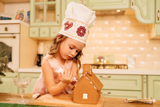 a cute little girl decorates a ginger house with icing. 