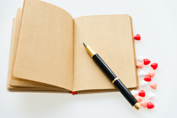 blank note card and pen surrounded by heart shape candy