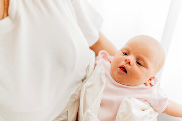 Mom with her baby newborn infant kid child at home take care in the bedroom put on clothes. Woman family women's health and maternity
