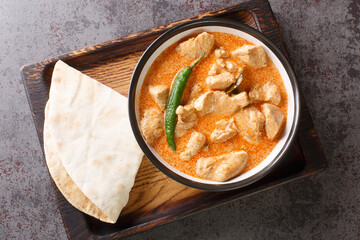 Kukul mas is a traditional Sri Lankan chicken curry made with a onions, ginger, garlic, turmeric, garam masala, chili powder, coconut milk, tomato in the bowl on the table. Horizontal top view