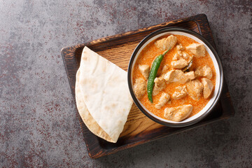 Spicy Kukul Mas chicken breast curry with coconut milk and spices close-up in a bowl on a wooden tray. Horizontal top view from above